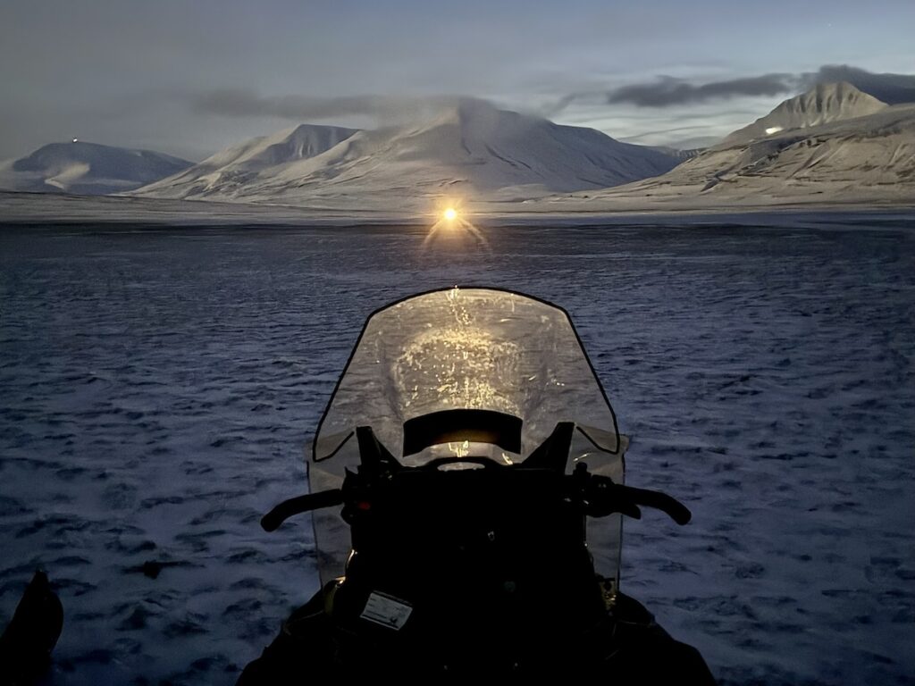 A snowmobile in a snow covered valley in Svalbard.