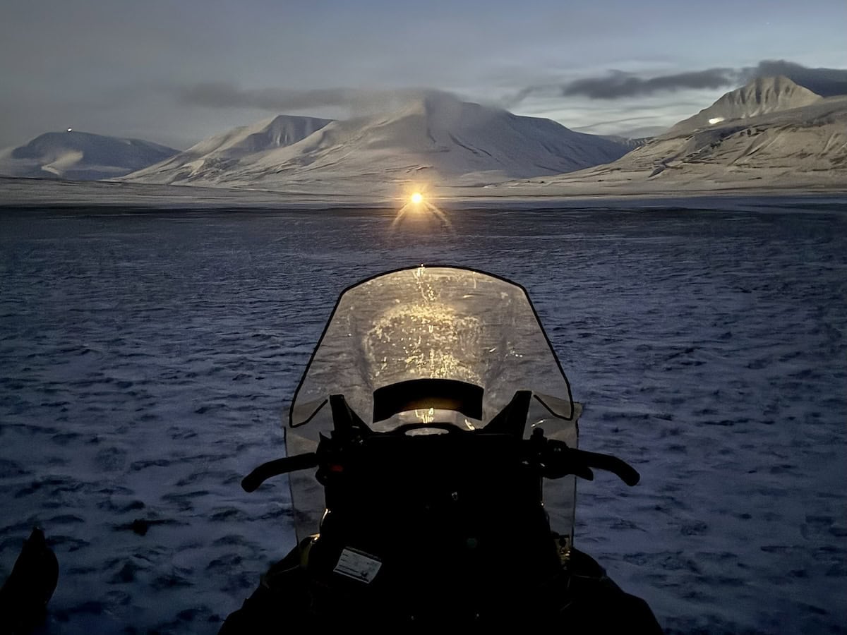 A snowmobile in a snow covered valley in Svalbard.