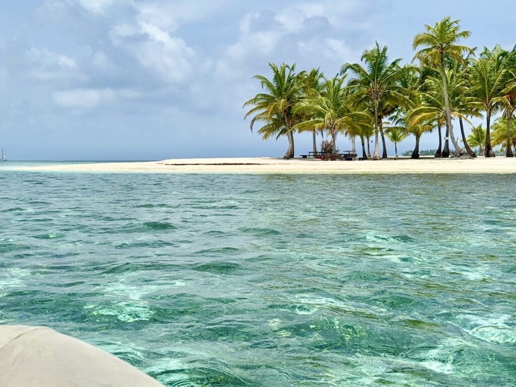 Boat sailing toward a tropical island in the San Blas Islands over crystal-clear turquoise water