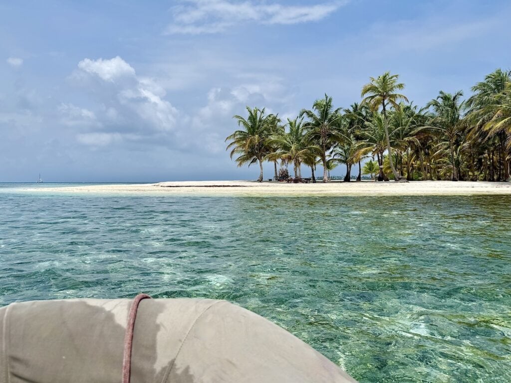 A dinghy approaching a small island full of palm tress in the San Blas Islands
